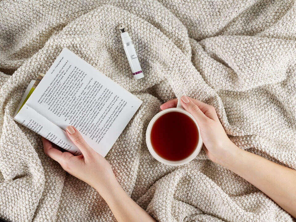 Hands in blanket with book, coffee and Dermalogica product | SalonCentric